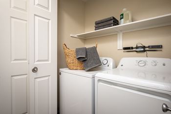 a laundry room with a washer and dryer and a door to the bathroom at Sundial Apartments, Wilsonville Oregon